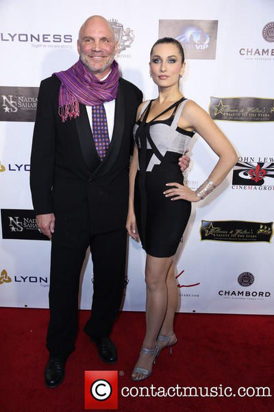 Man and woman posing on a red carpet event with a branded backdrop