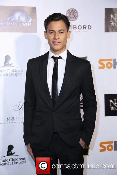 Man in a black suit standing against a branded backdrop