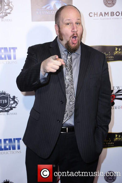 Man in a suit pointing at a branded backdrop