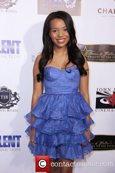Woman in a blue dress standing in front of a promotional backdrop