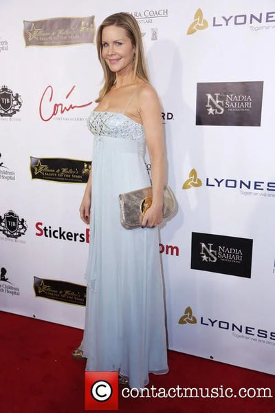 Woman in a strapless dress on a red carpet with promotional backdrop