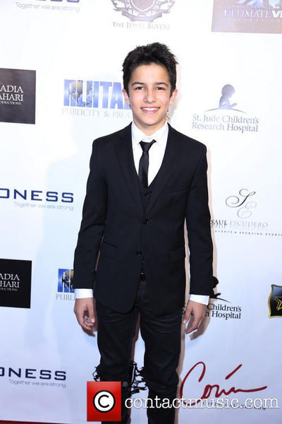 Man in a black suit standing in front of a promotional backdrop