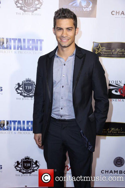 Man in a black suit standing in front of promotional backdrop