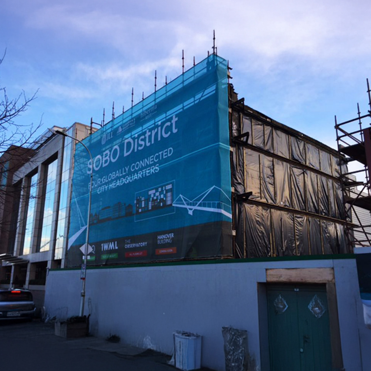 Building under construction with a large blue advertisement on the side.