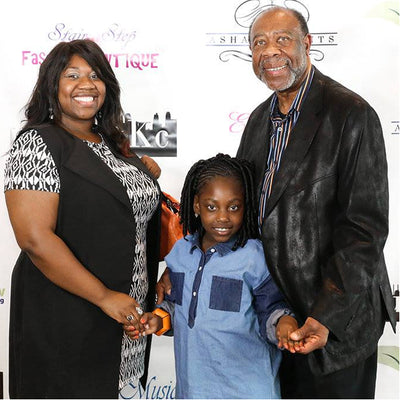 Family of three posing together in front of a branded backdrop
