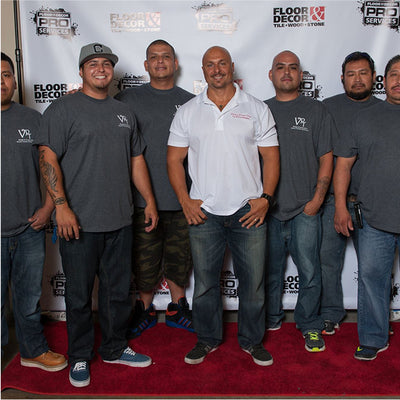 Group of men posing in front of a branded backdrop with 'Floor & Decor' and 'Pro Services' logos.